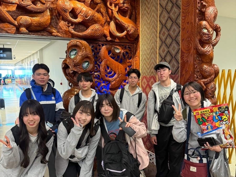 International students gathered in front of an intricately carved Māori pou — a welcome to Aotearoa.